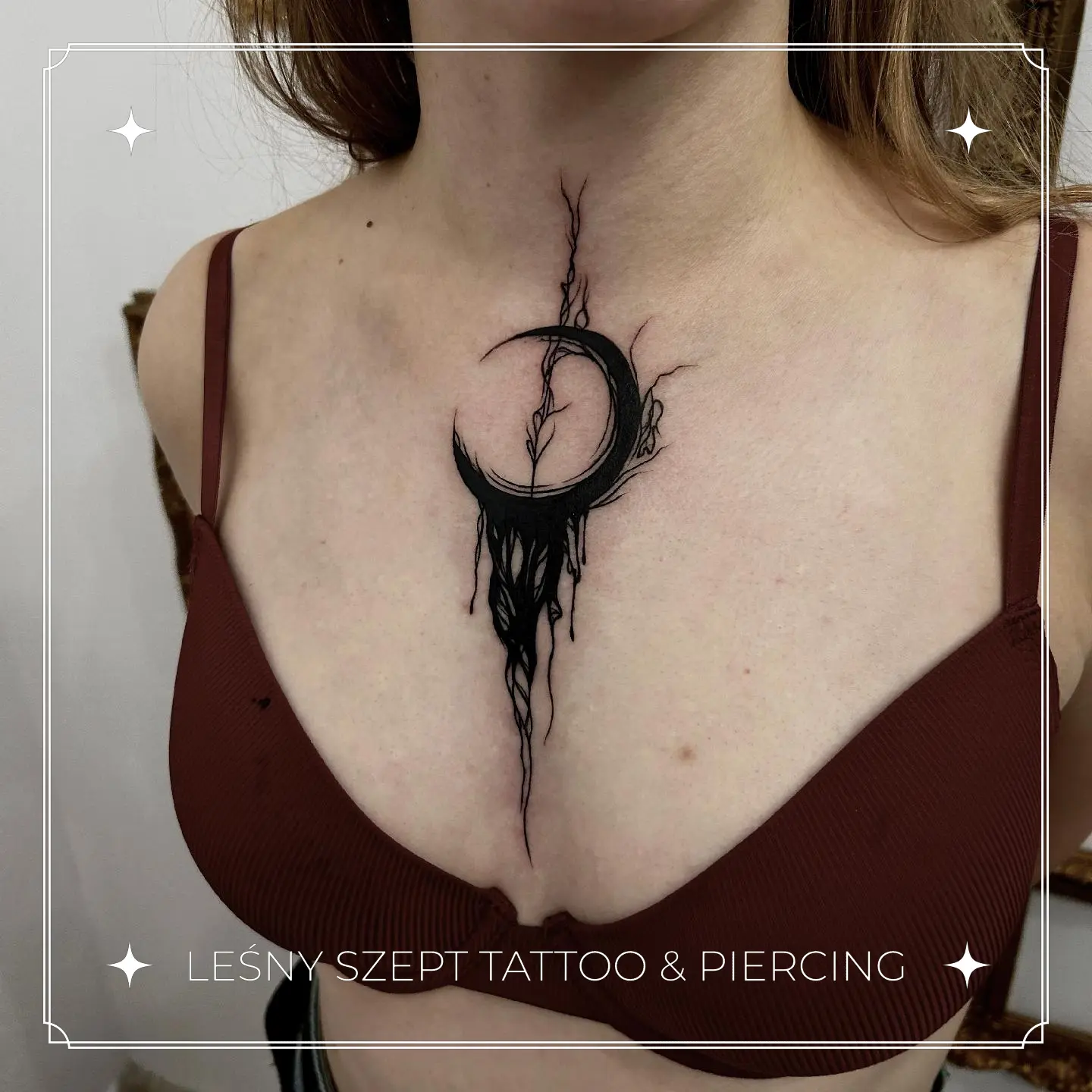 Czarny tatuaż kapiącego półksiężyca z abstrakcyjnymi korzeniami, na środku klatki piersiowej