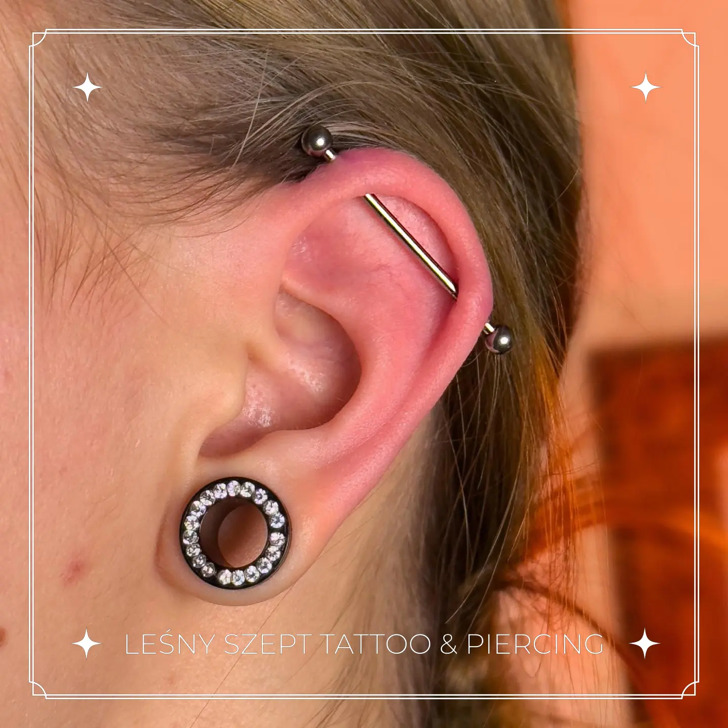 Przekłucie ucha z kolczykiem industrialnym i świecącym tunelem