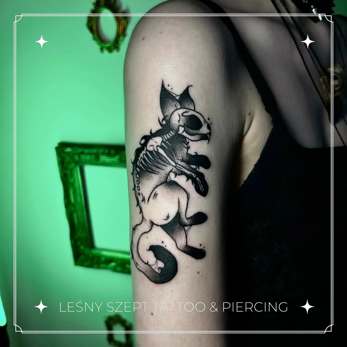Tatuaż fantazyjnego stwora przypominającego kota ze szkieletem, w stylu blackwork na ramieniu