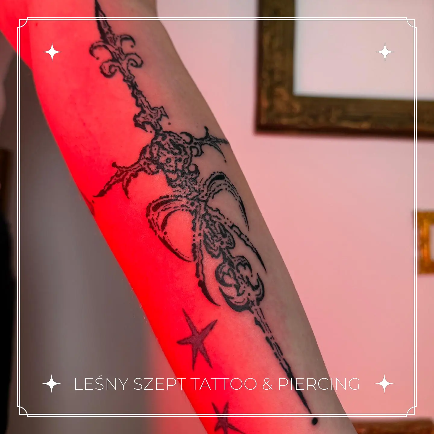 Tatuaż gotyckiego krzyża z kokardą i gwiazdkami w stylu blackwork na przedramieniu