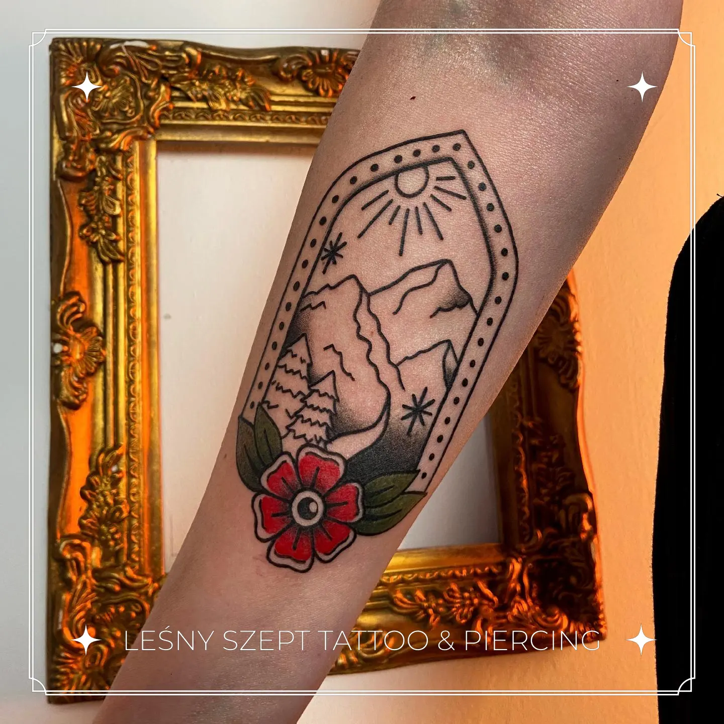 Tatuaż gór, lasu i kwiatu w ramce na przedramieniu