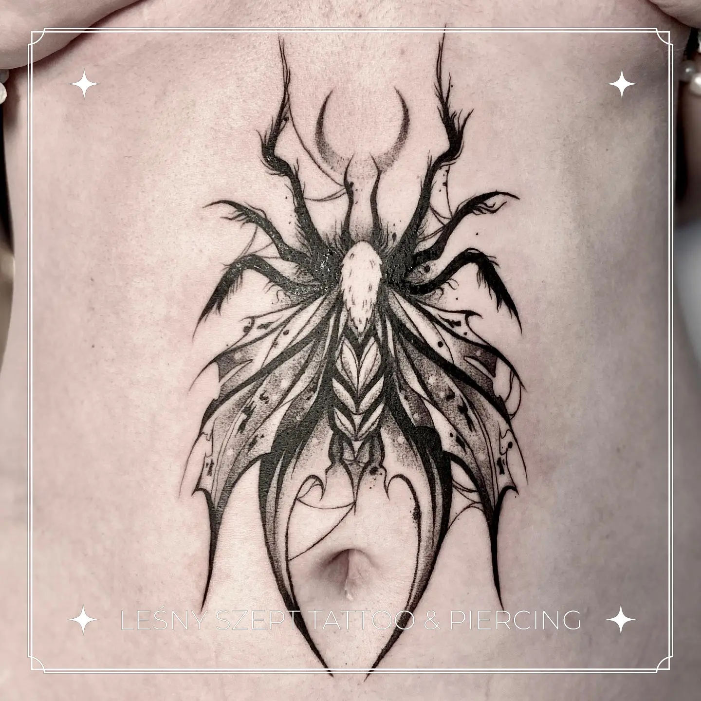Gotycki tatuaż motyla z dynamicznymi skrzydłami, umieszczony na brzuchu