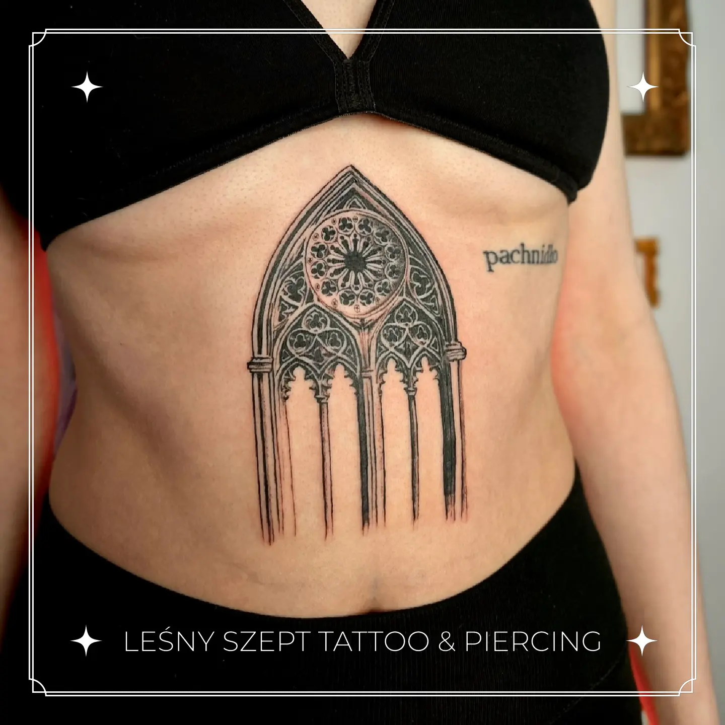 Tatuaż gotyckiego okna katedry na brzuchu
