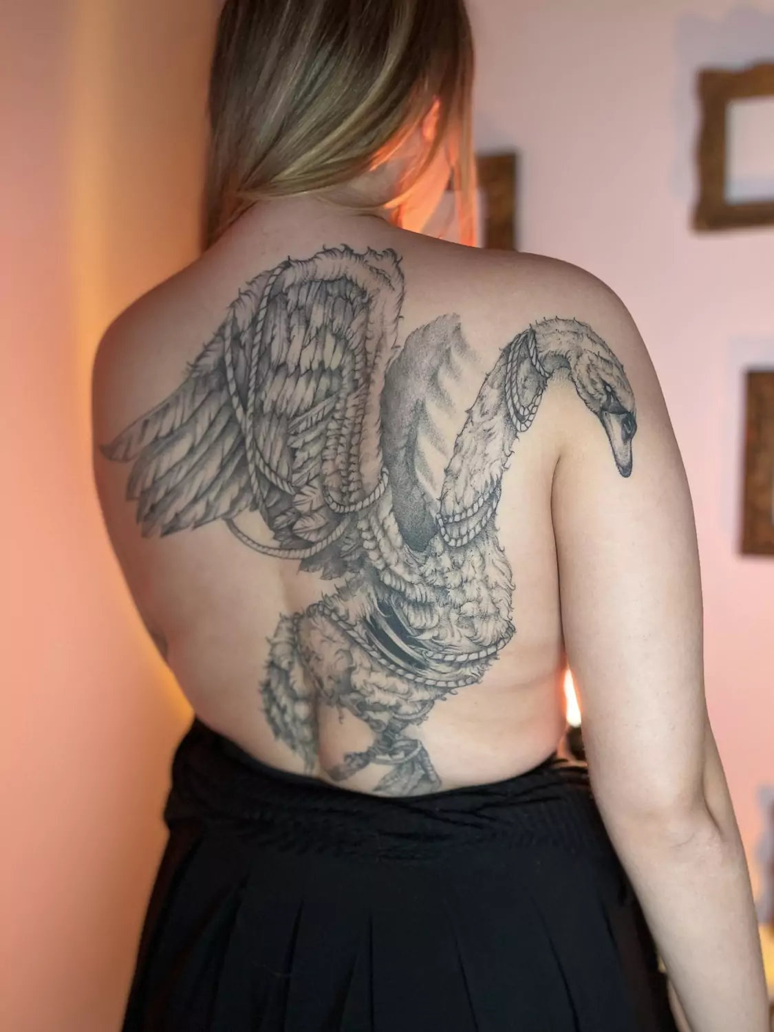 Realistyczny tatuaż ptaka z rozpostartymi skrzydłami na całe plecy, wykonany w czerni